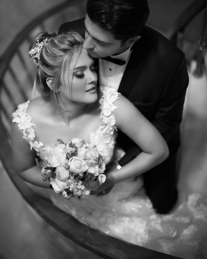 Elegant black and white photo of a bride and groom embracing on a staircase.